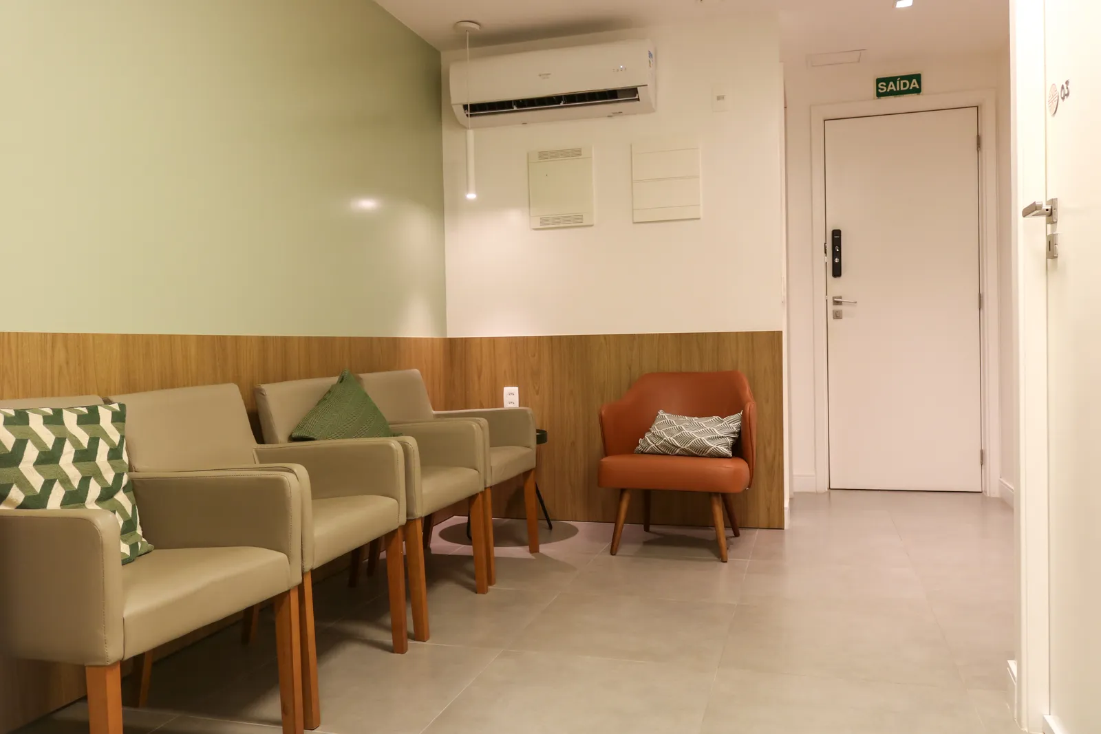 Sala de espera da Corcovado, com parede verde e poltronas em tons de areia e terracota